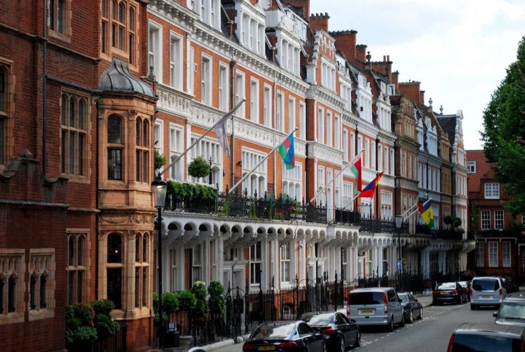 A road in London with red brick buildings and flags of different countries where their Embassy is located.